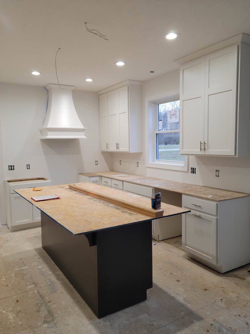 Kitchen with white shaker cabinets, marble countertop, stainless steel sink, tile backsplash, and light wood flooring