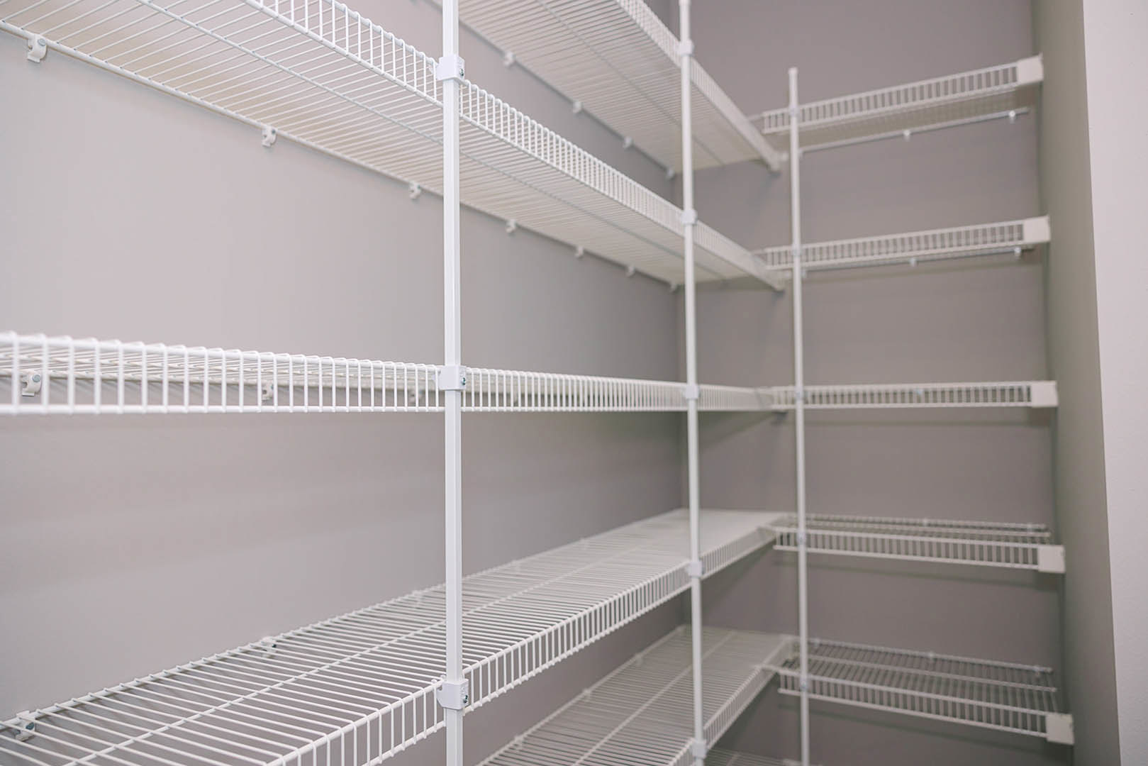 White wire shelving unit mounted on a gray wall in a residential room.