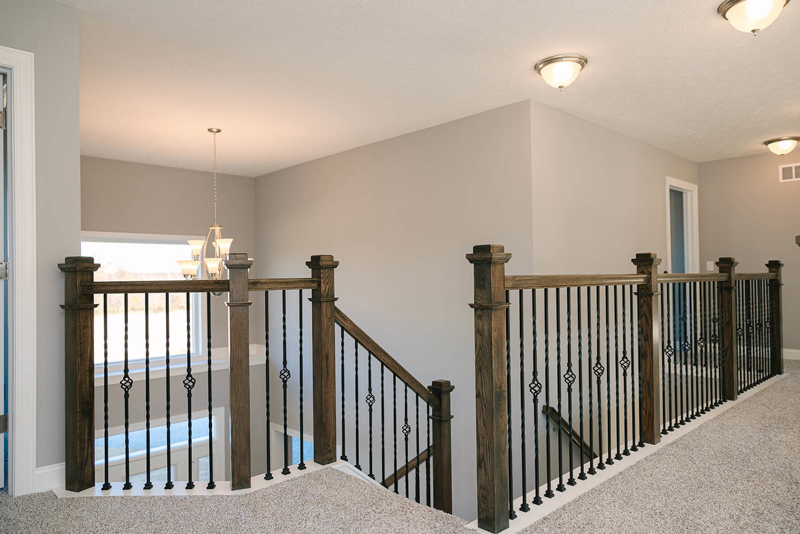 Wooden staircase with matching handrail and balusters, light fixture mounted on plaster wall, hardwood flooring and white ceiling visible