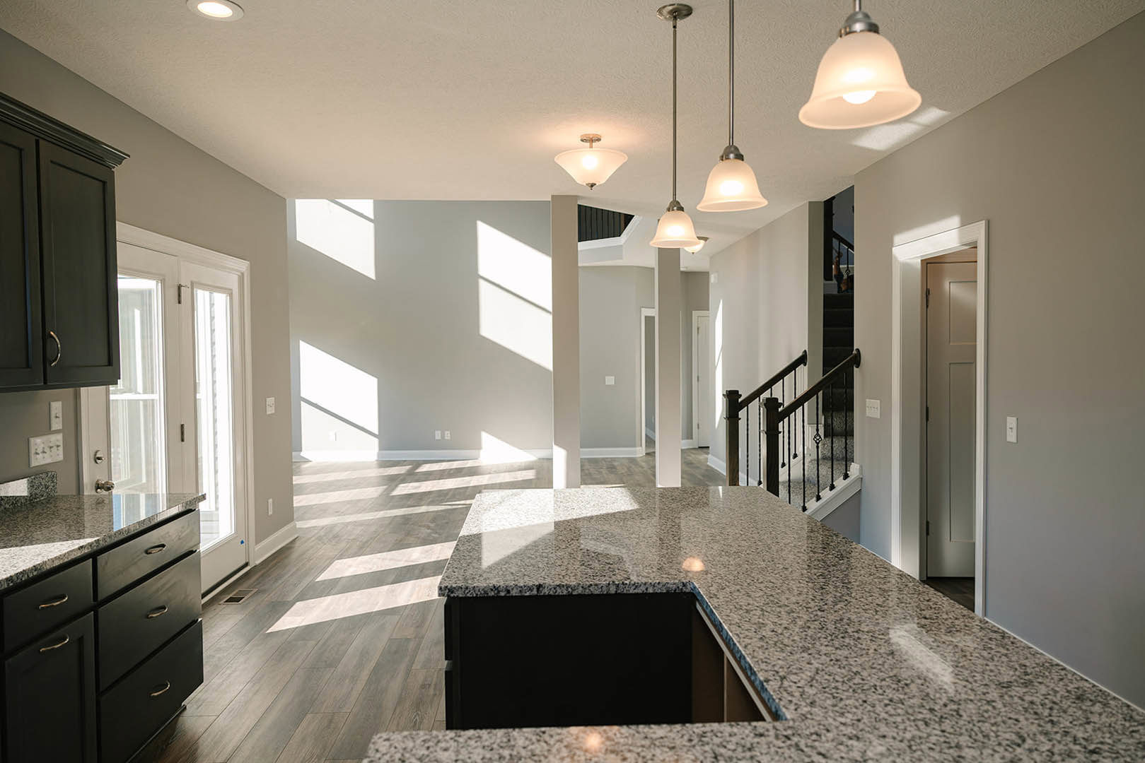 Open-concept kitchen and living room featuring marble countertops, white cabinetry, stainless steel appliances, tile backsplash, wood flooring, and recessed lighting