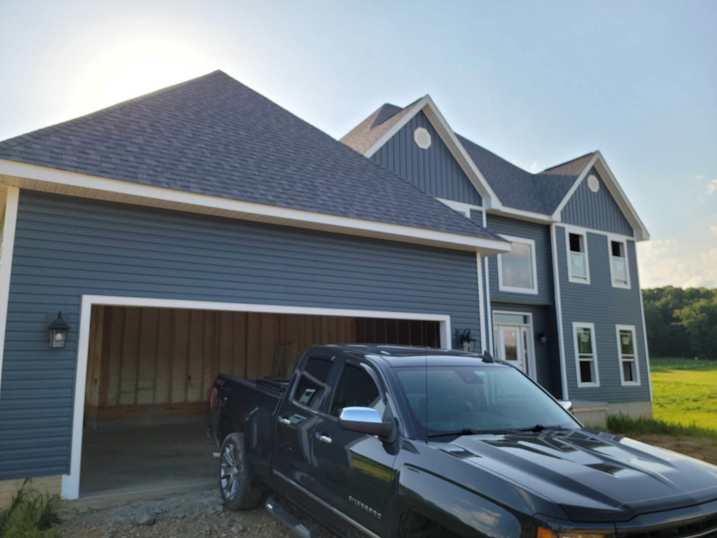 Black pickup truck parked inside a finished garage with concrete floor, overhead lighting, and white walls