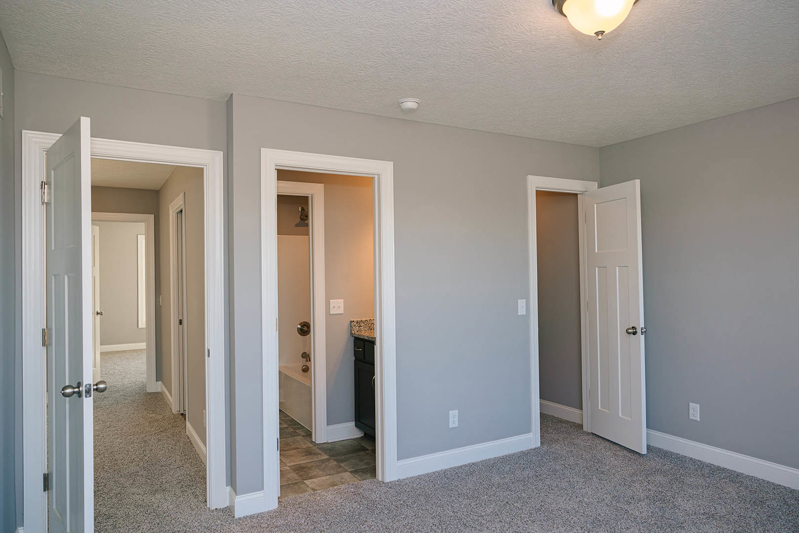 Bathroom with white door open to hallway, freestanding bathtub, modern sink vanity, light fixture, and smoke detector on plaster ceiling