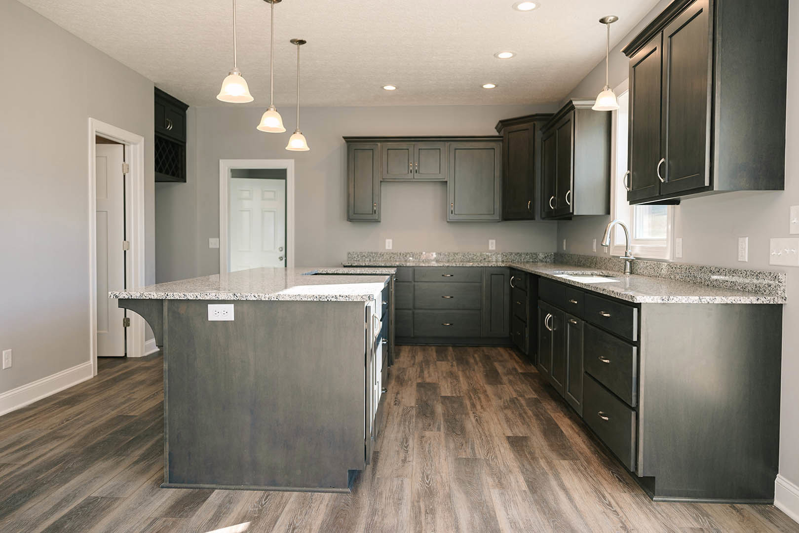 Kitchen with dark wood cabinets, polished granite countertops, tile flooring, stainless steel sink, and a central island with marble top