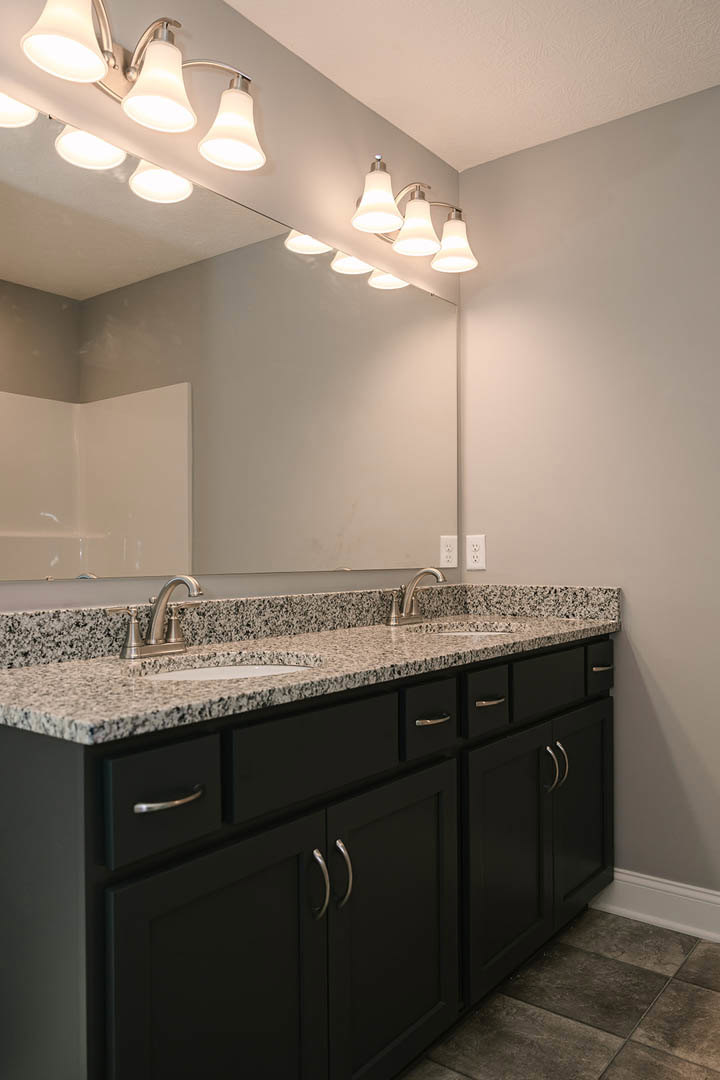 Bathroom featuring granite countertop, expansive mirror with overhead lighting, tile flooring, white walls, and modern sink fixtures