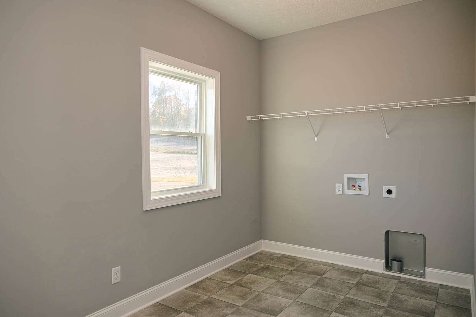 Bathroom with tile flooring, plaster walls, window overlooking trees, metal towel rack, shower fixtures with red and blue faucets, and a white tile accent.