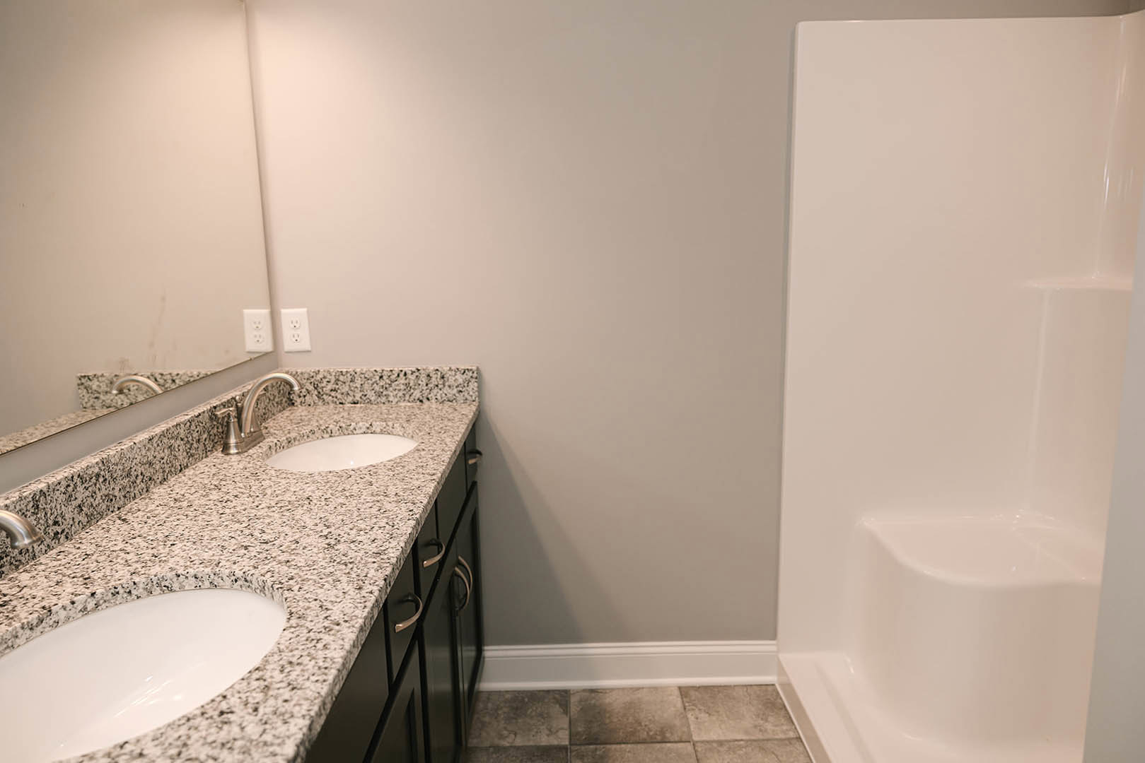 Bathroom with marble countertops, dual sinks, freestanding bathtub, white tile walls, and chrome fixtures