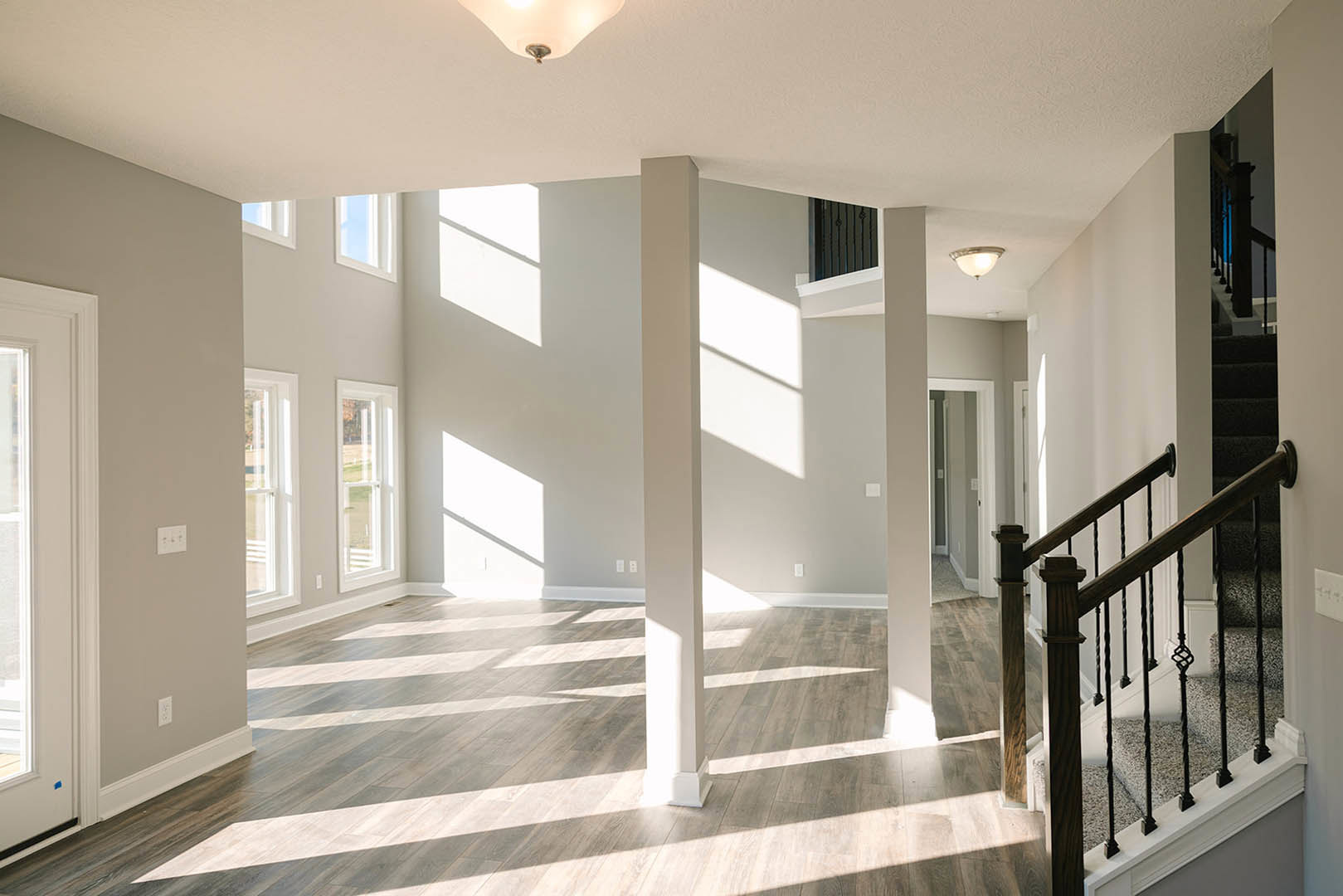 Spacious foyer with hardwood staircase, white balusters, crown molding, and recessed ceiling lights; walls painted soft white.