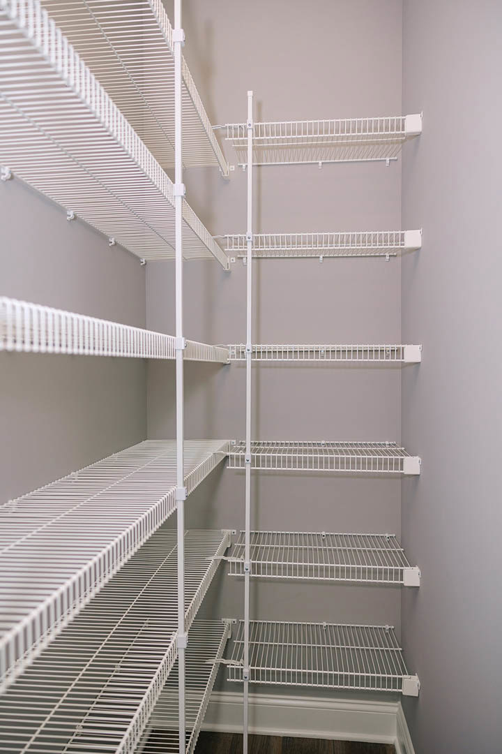 White metal shelving unit with wire bars against a white wall in a modern interior room