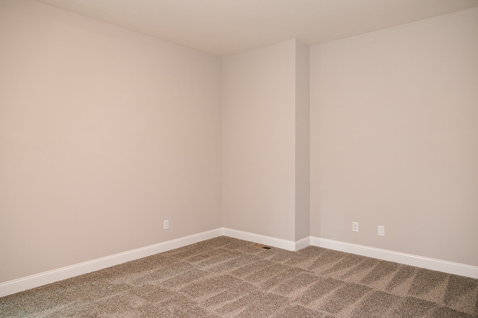 Carpeted room with white walls, white ceiling, and a floor vent in the corner