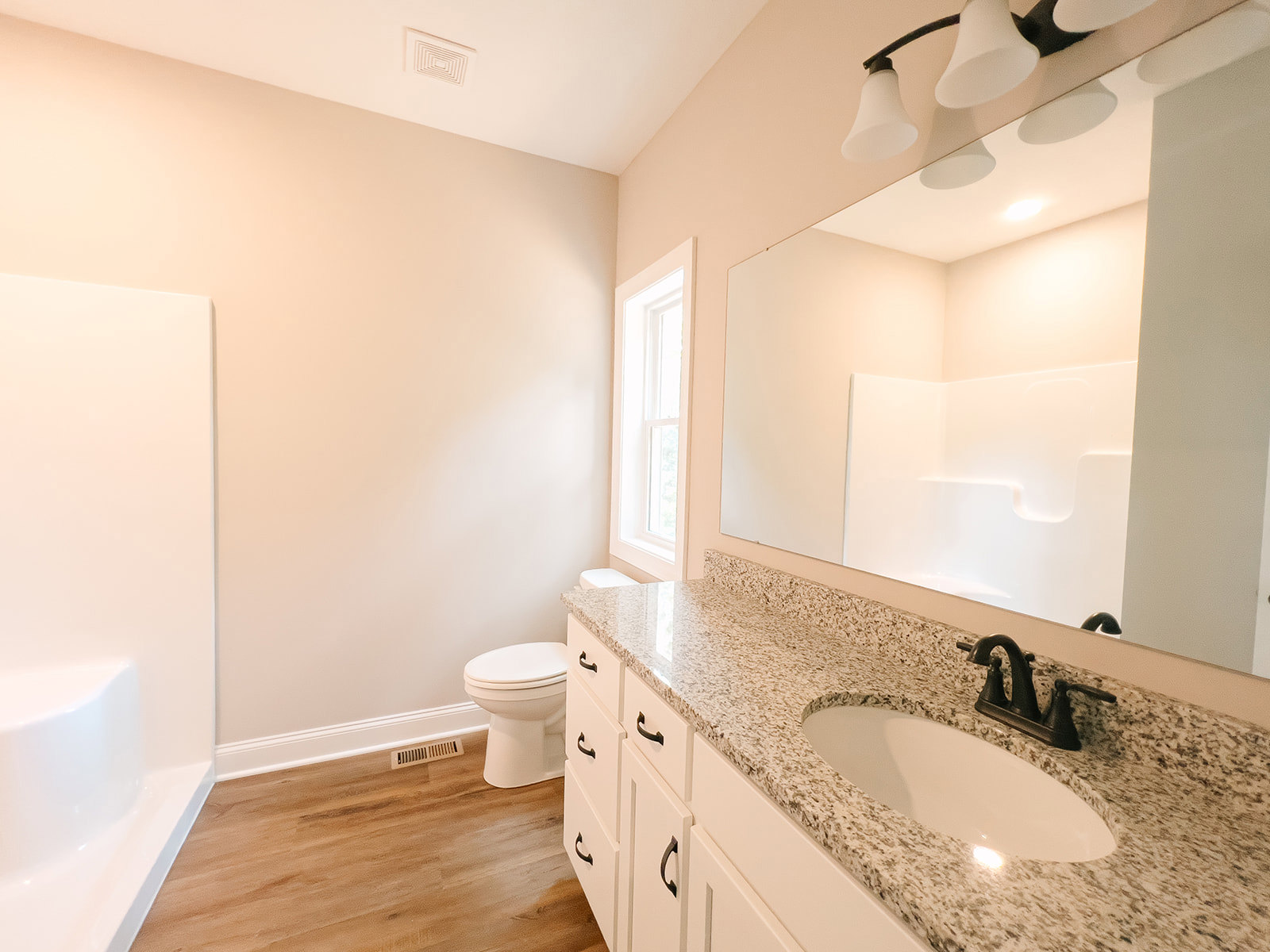 Marble countertop with undermount sink and chrome faucet, white toilet, tile flooring, sunlight streaming through window