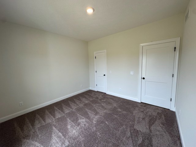 Carpeted room with two white doors, light-colored walls, and simple baseboard trim