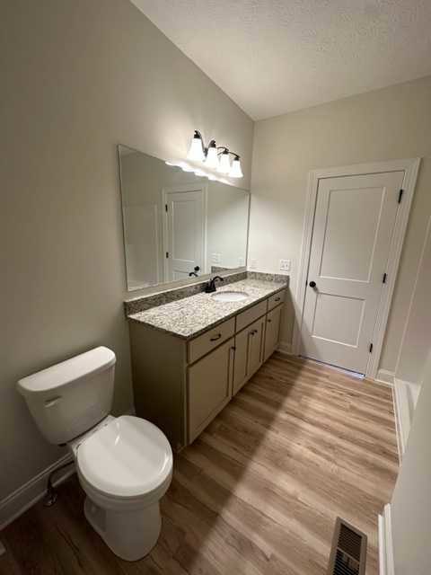 White toilet with seat down next to white sink, light tile floor, white door with black knobs, neutral wall color