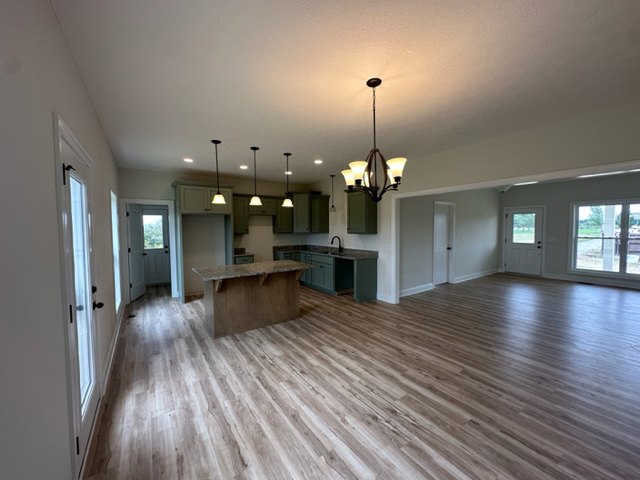 Kitchen with a central island featuring a light countertop, hardwood floors, plaster walls, and recessed ceiling lighting