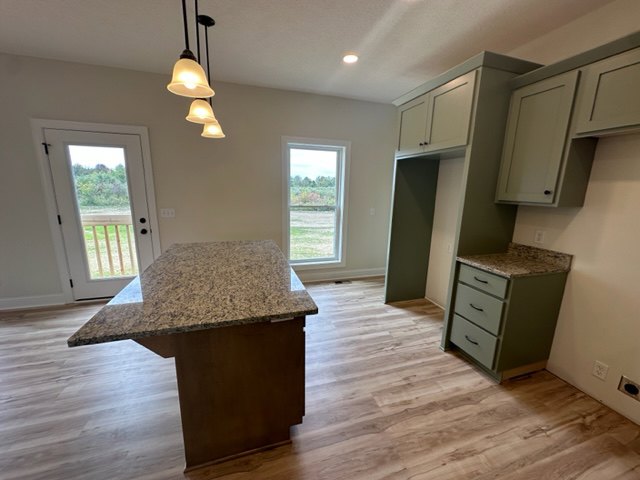 Marble countertop kitchen with wooden cabinets, dining table, light tile flooring, and neutral walls