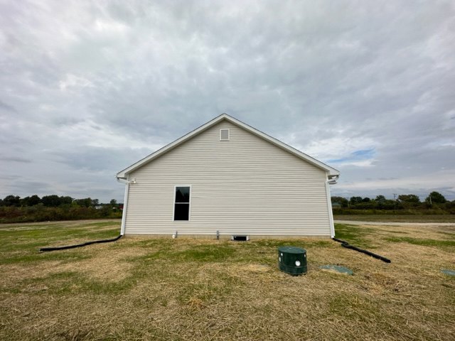 White siding house with green trash can and garden hose on grassy lawn, cloudy sky overhead