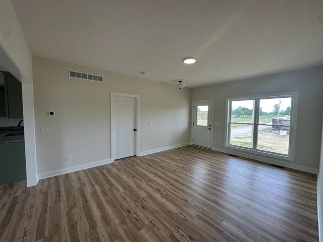 Wood flooring in a bright room with white walls, a paneled door, and simple ceiling trim