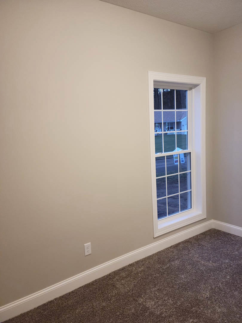 White-framed window set in a white wall, white ceiling above, beige carpeted floor below
