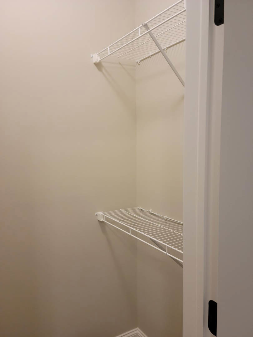 White wire shelf mounted on plaster wall in corner of closet interior