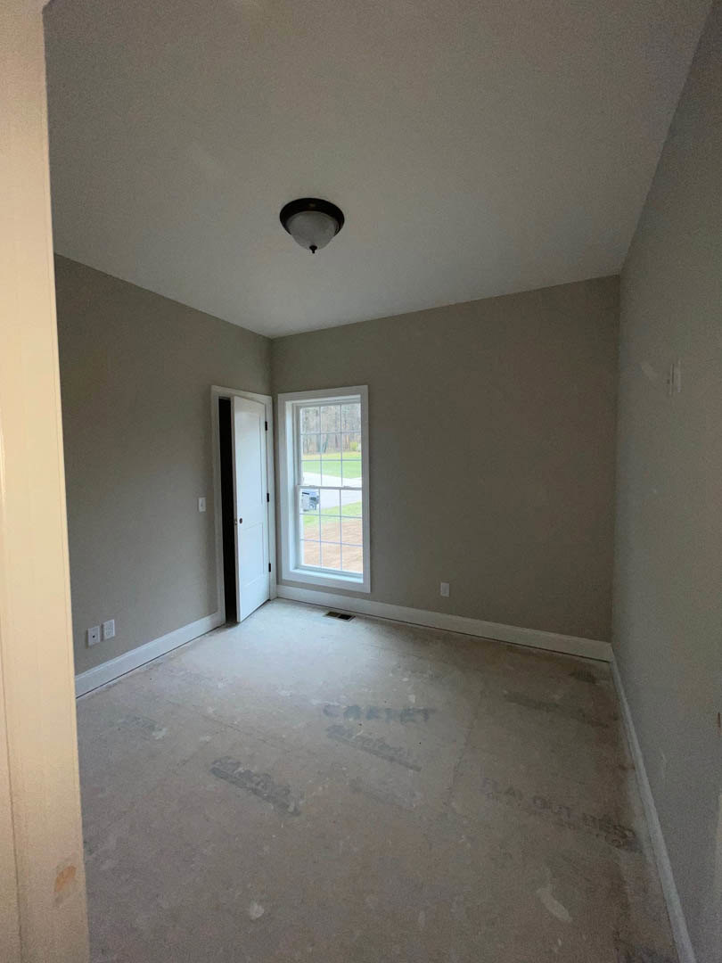 Concrete floor with handwritten markings, white door framed in black, large window overlooking green lawn, minimalist ceiling light fixture, smooth plaster walls