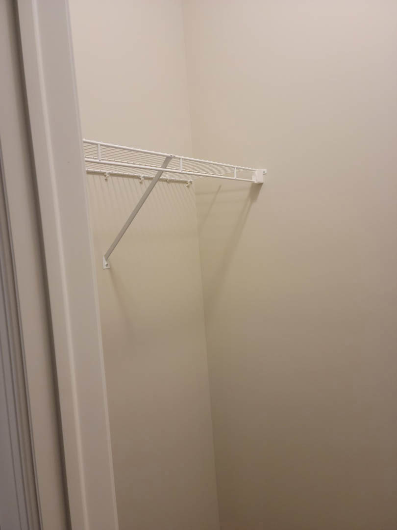 White built-in shelf with metal rod mounted on smooth plaster wall in bathroom.