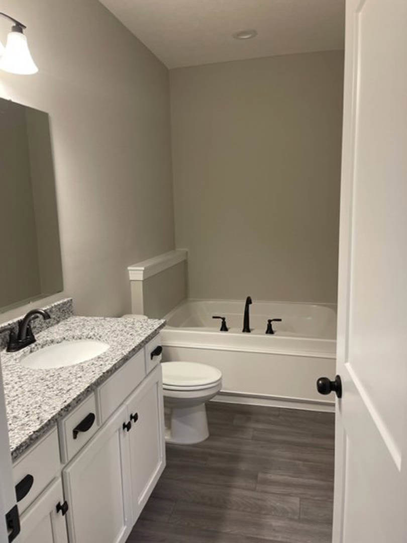 Modern bathroom featuring a white toilet, rectangular sink with chrome faucet, light-colored tile flooring, white walls, and a soap dispenser on the countertop.