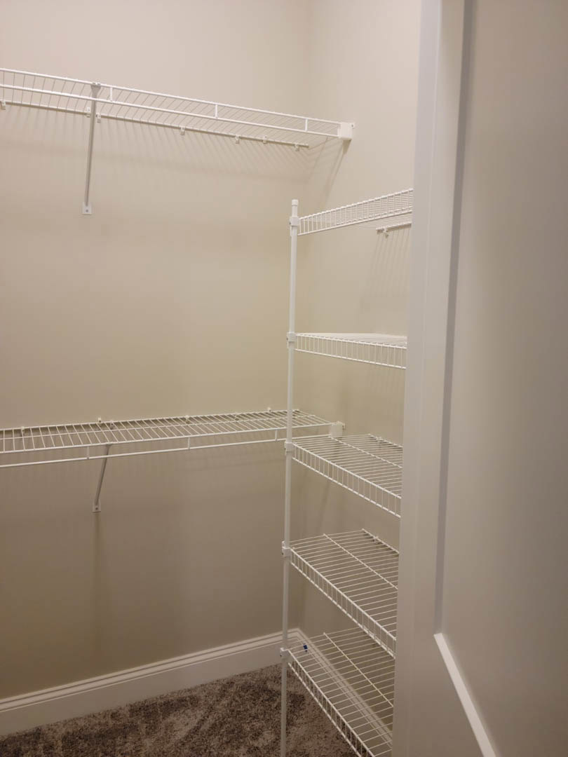 Walk-in closet with white wire shelving, carpeted floor, and smooth white walls