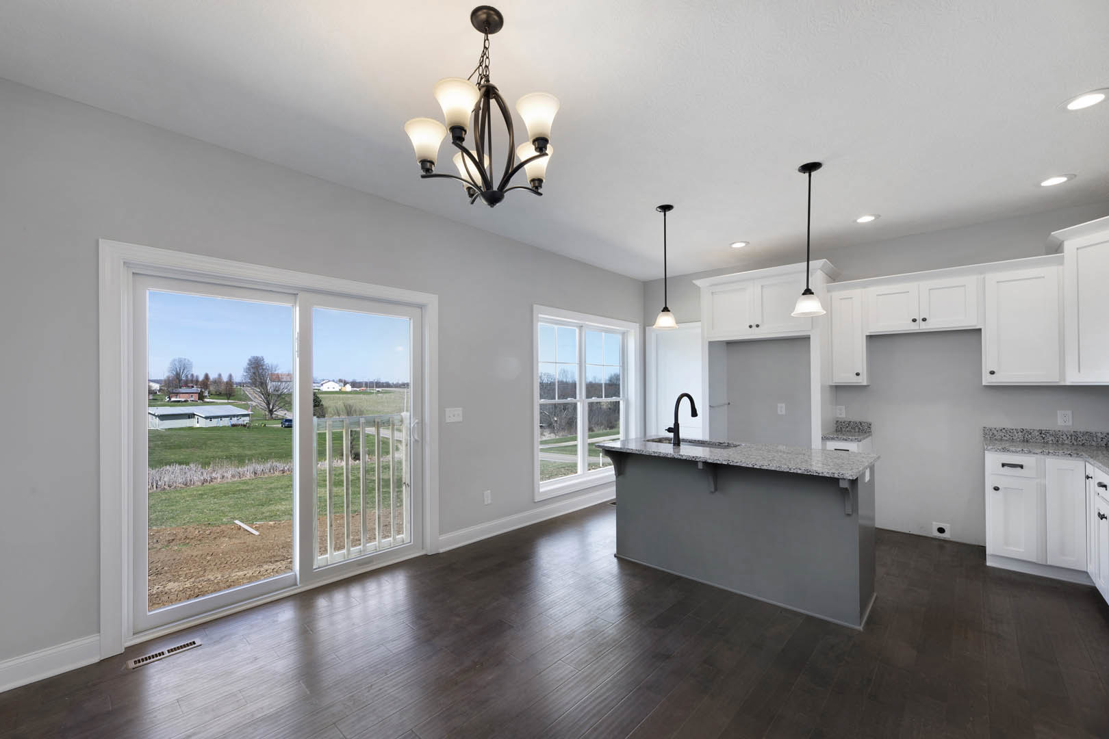 Modern kitchen featuring a dark wood floor with white trim, large window above the sink, white cabinetry, stone countertop bar, stainless steel appliances, and a close-up of a