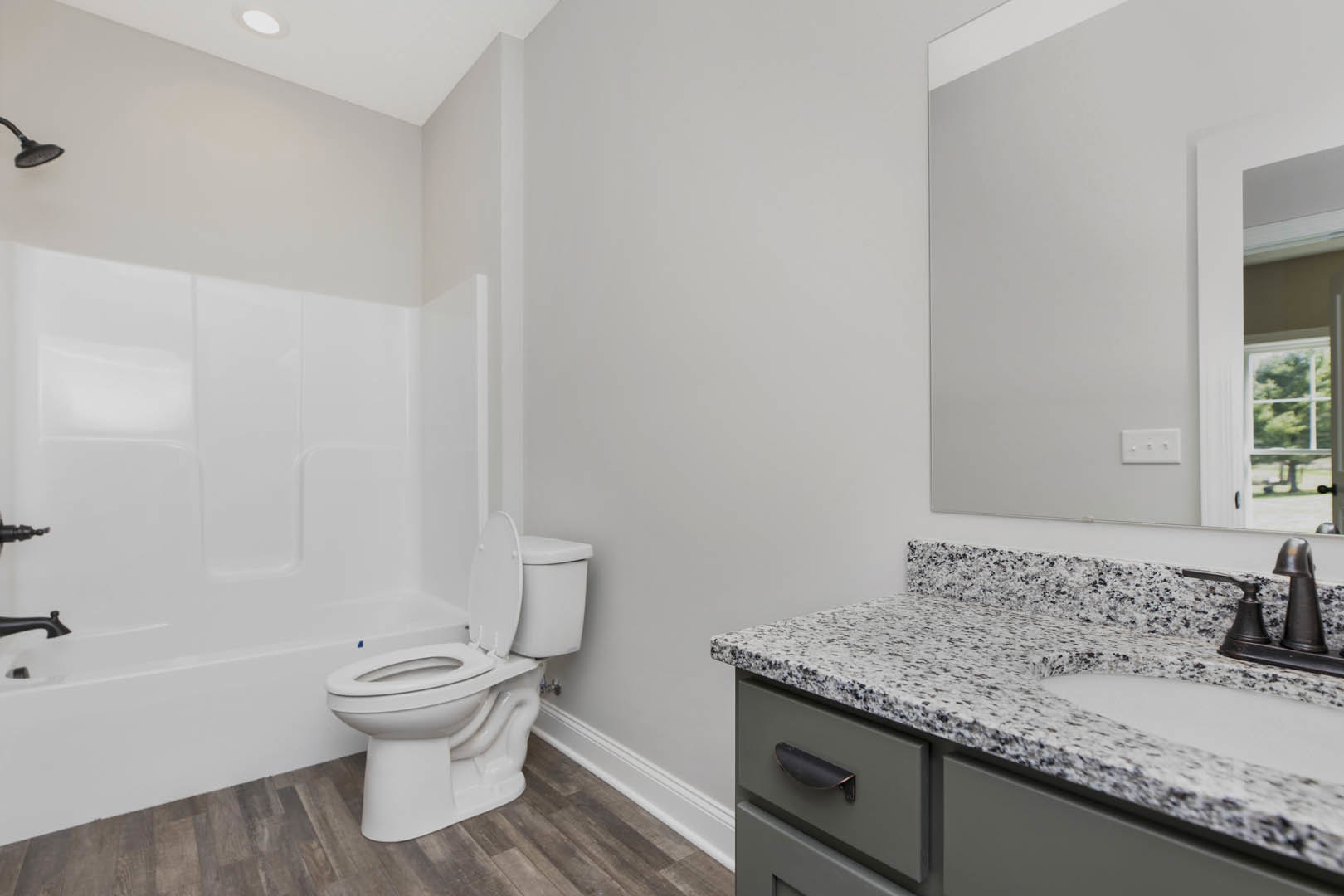 Modern bathroom featuring a white toilet, rectangular sink set in a stone countertop, tiled walls, chrome faucet, and a white light switch with round knobs.