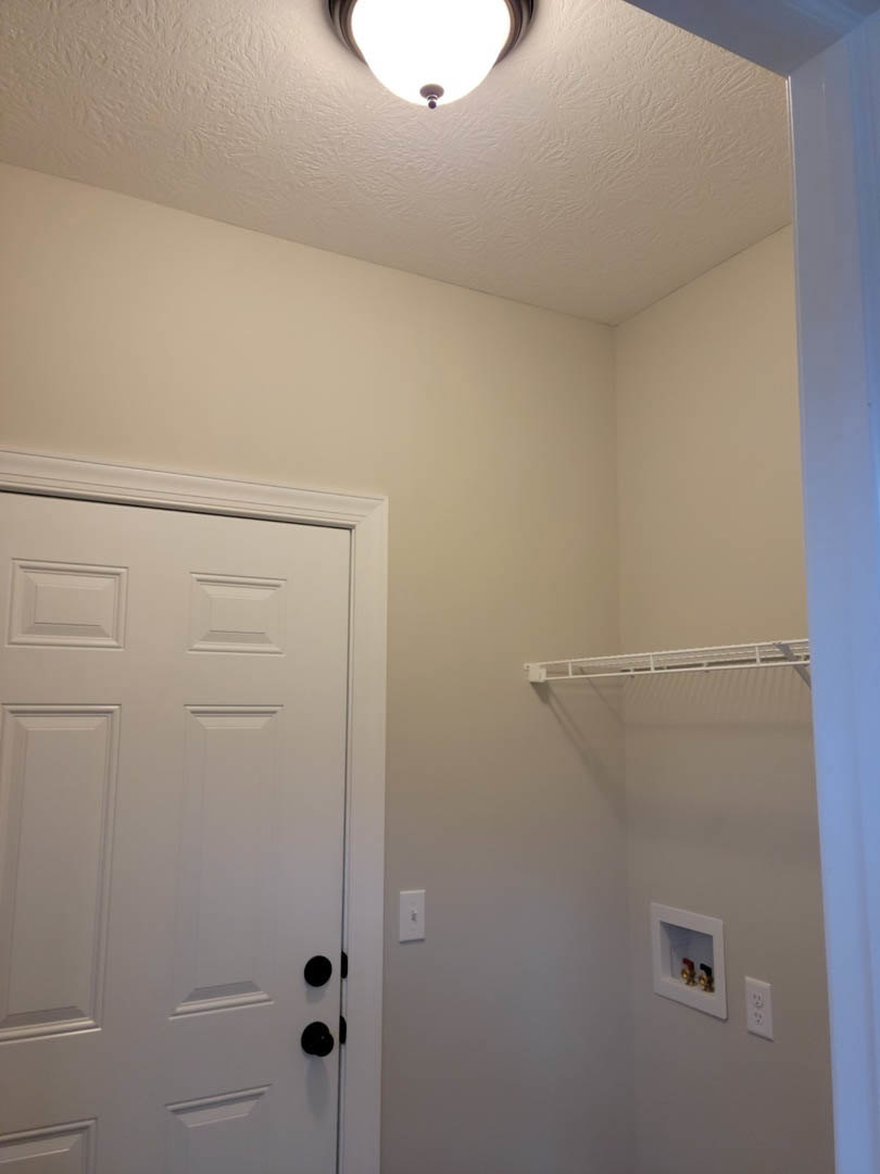Walk-in closet with white paneled doors, white walls, and black door hardware