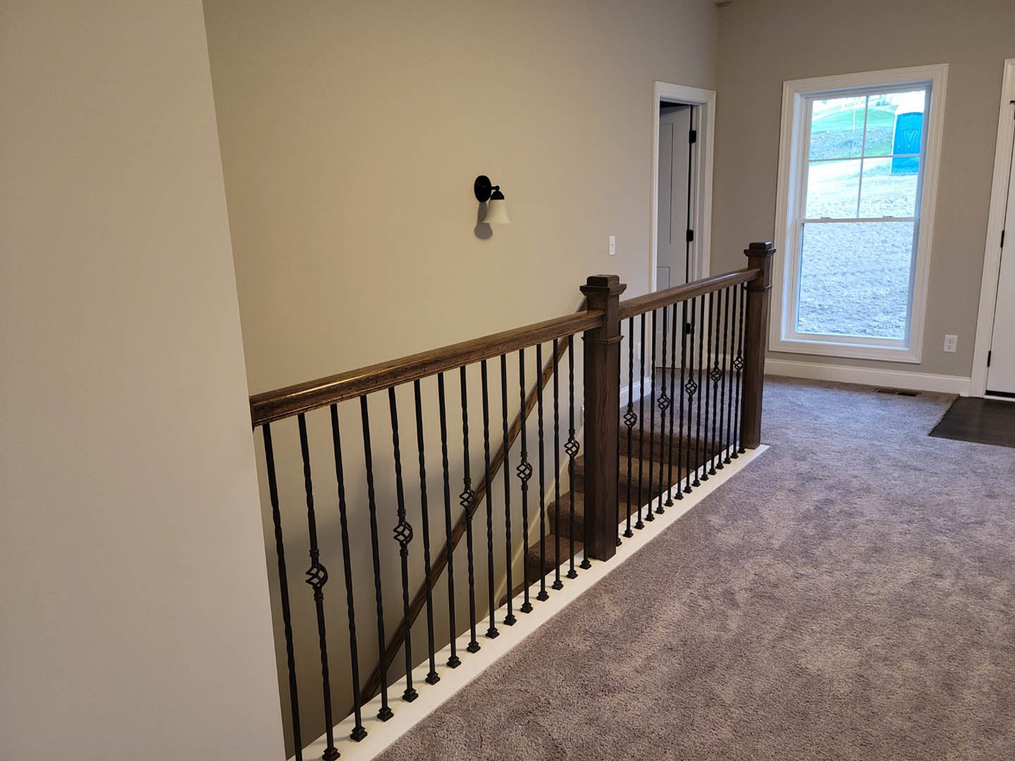 Carpeted staircase with white railing, blue door and window, black and white lamp, neutral plaster walls