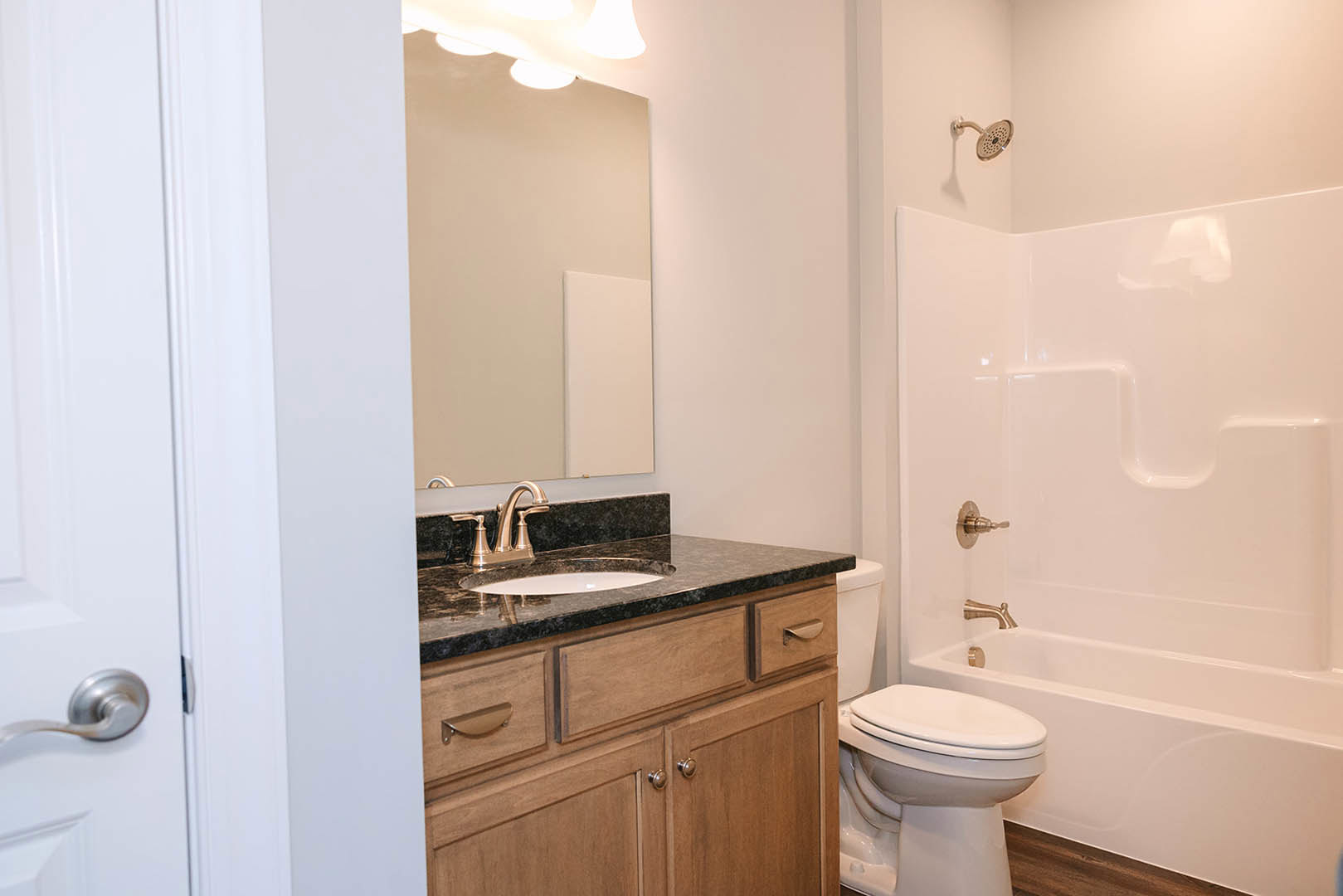 Modern bathroom featuring white tile walls, a sleek countertop with integrated sink, chrome faucet, white toilet, and minimalist cabinetry
