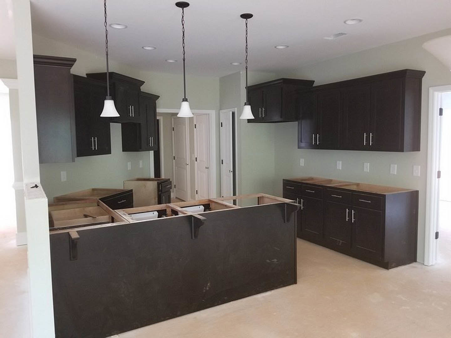 Kitchen with dark wood cabinets, black countertop, tile backsplash, stainless steel sink, and white lamp shade on a pole