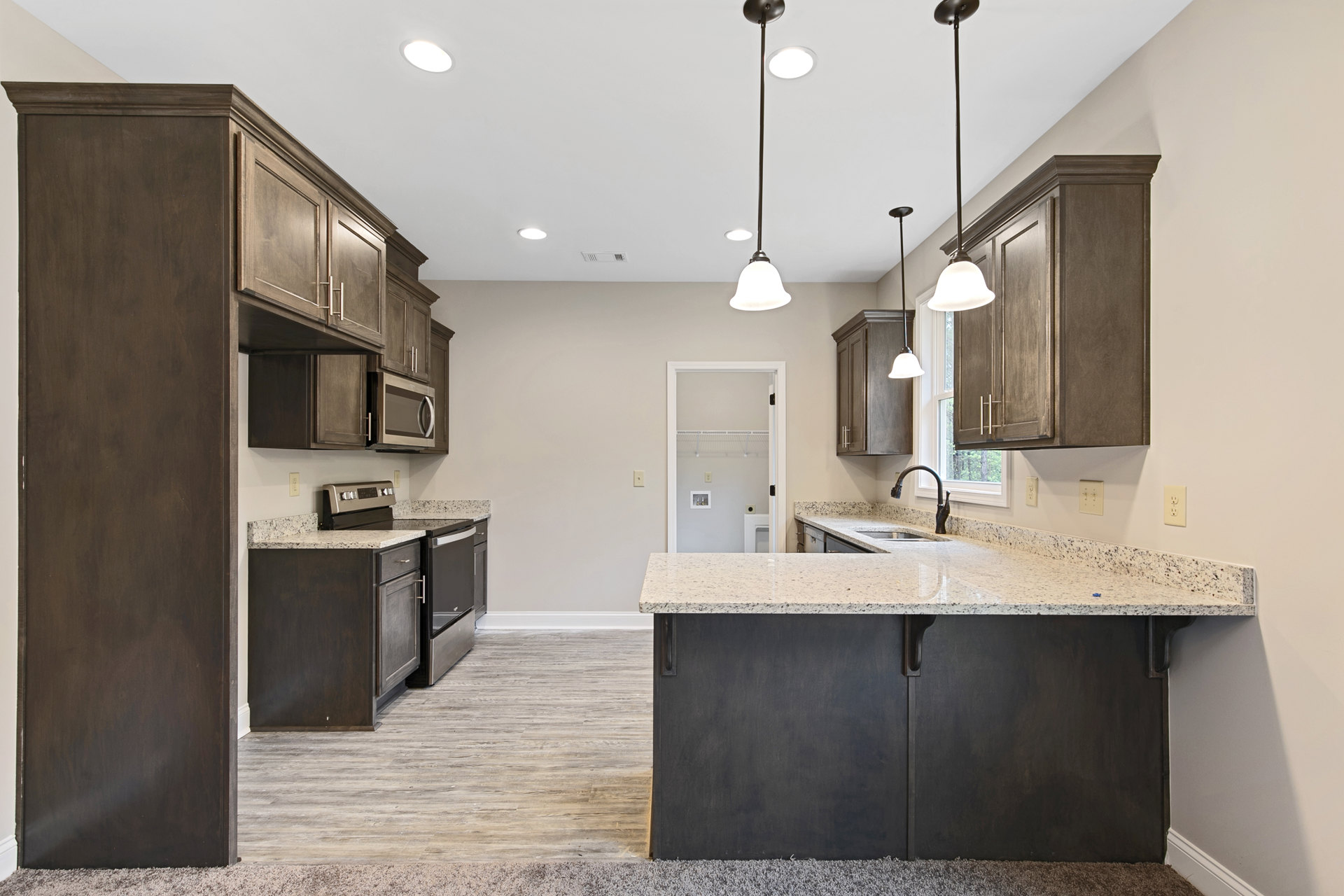 Kitchen with granite countertops, wood flooring, white cabinetry, stainless steel appliances, and a built-in microwave above the stove.