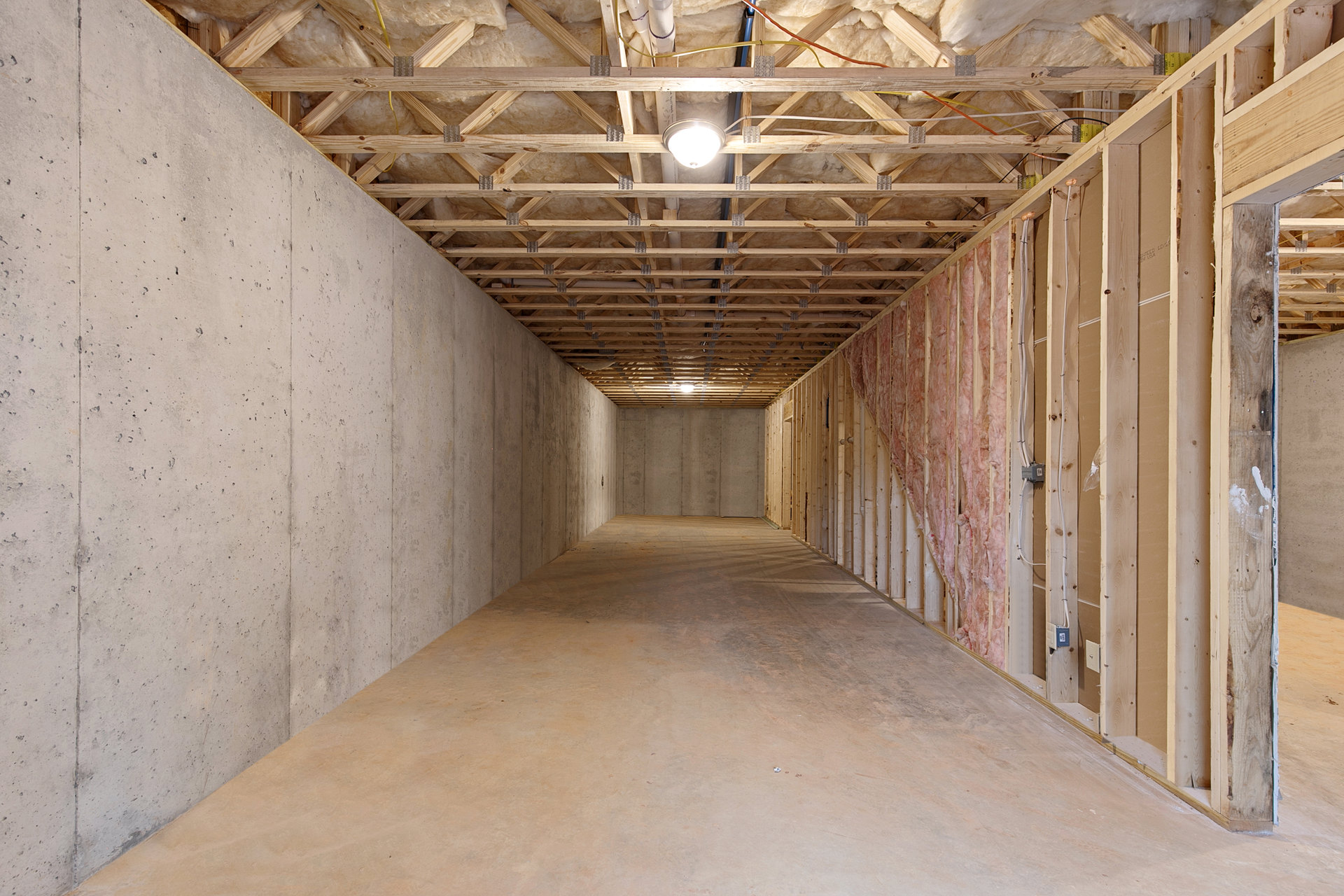 Long hallway with polished concrete floor, exposed concrete ceiling, white plaster walls, and recessed ceiling light fixture