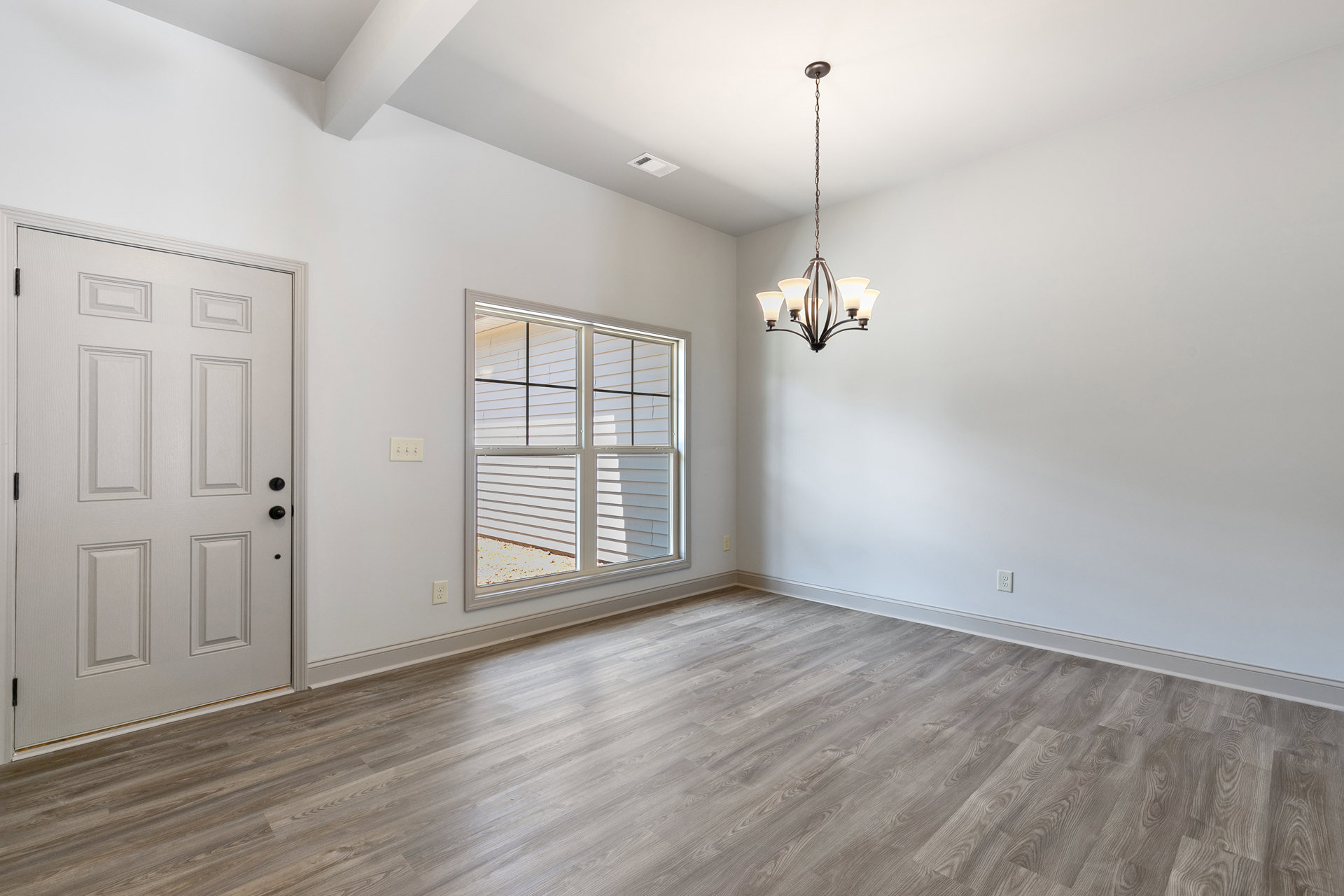 White paneled door with black knobs, wood flooring, plaster walls, decorative ceiling molding, and ornate chandelier hanging from ceiling.