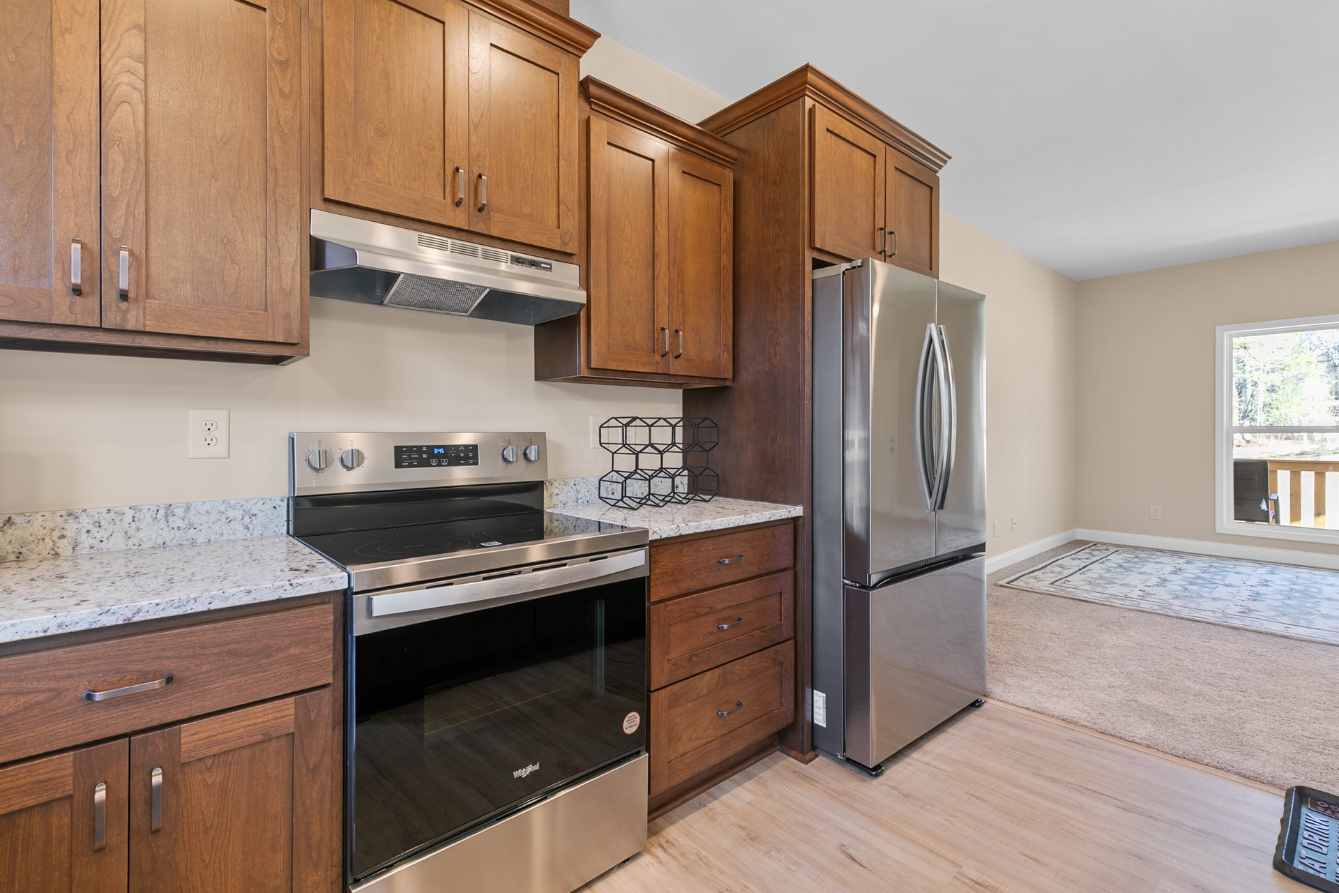 Kitchen with light wood cabinets, stainless steel refrigerator and oven, white countertops, and neutral tile backsplash