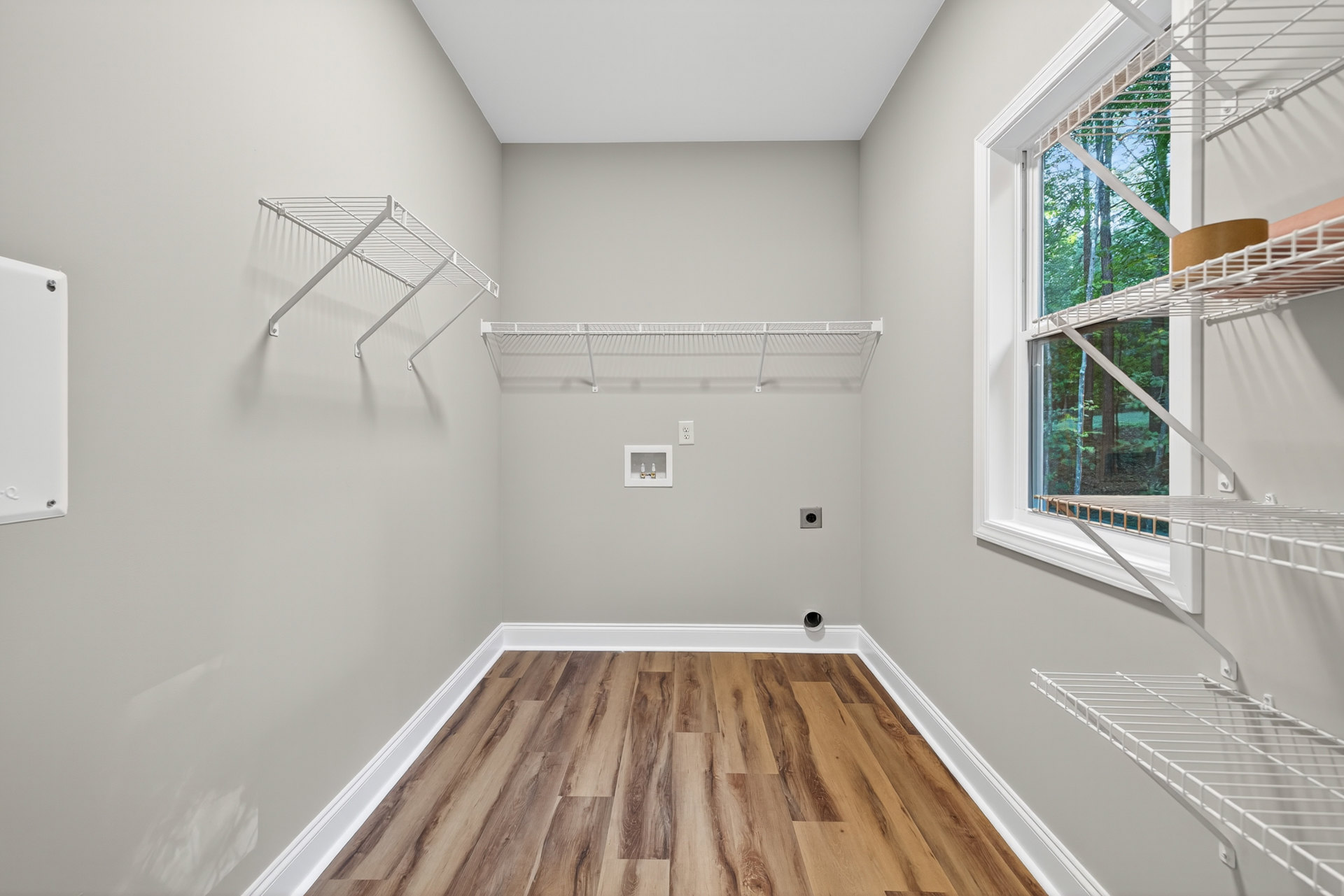 Wood floor room with white walls and a white wire shelving unit mounted along one wall