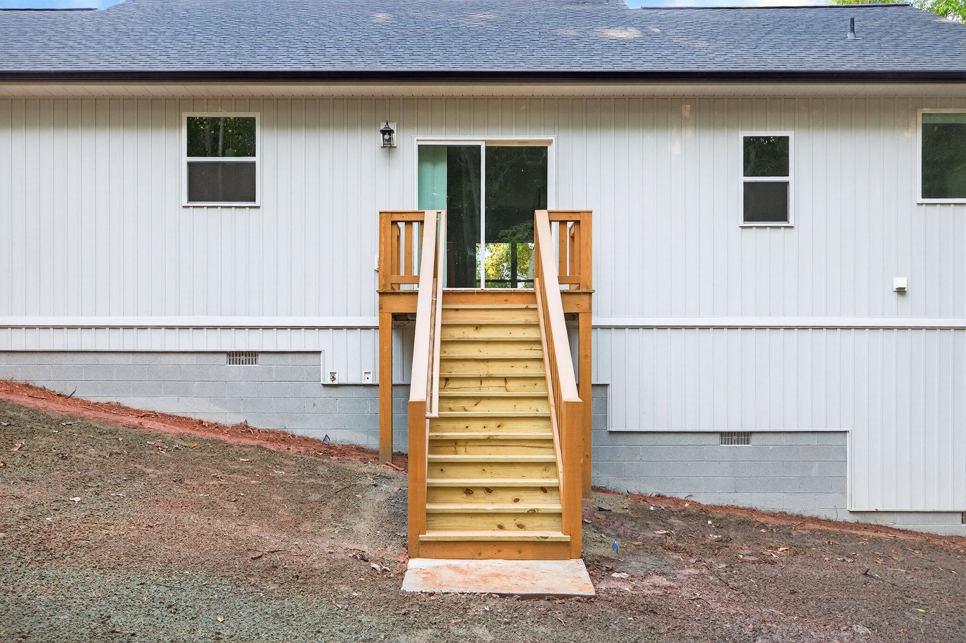 Wooden exterior staircase leading to a porch, surrounded by siding, glass door, screened window, and landscaping plants