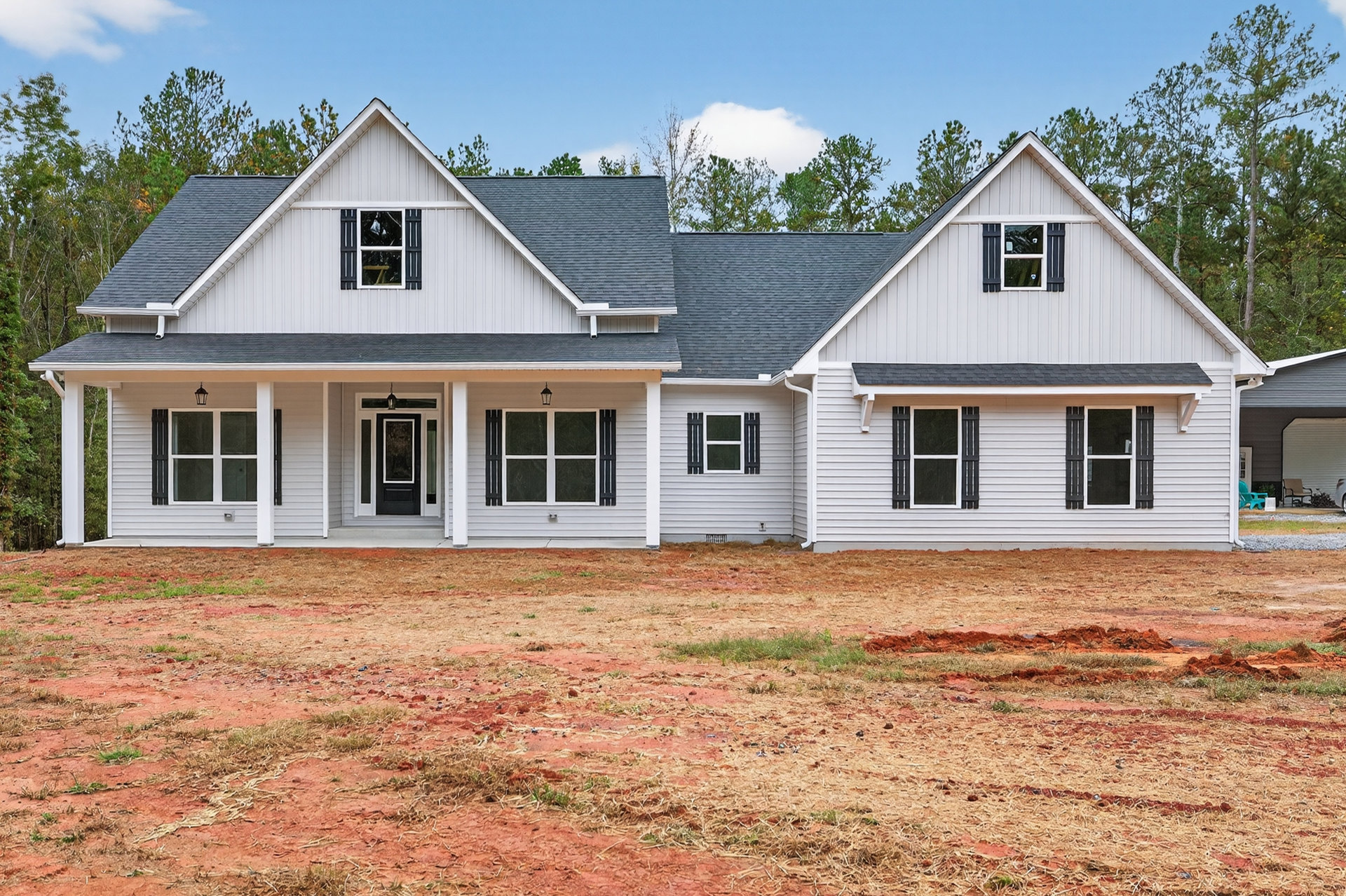Two-story home with white siding, black shutters, black front door, white-framed windows, fenced grassy yard, and cloudy sky in background