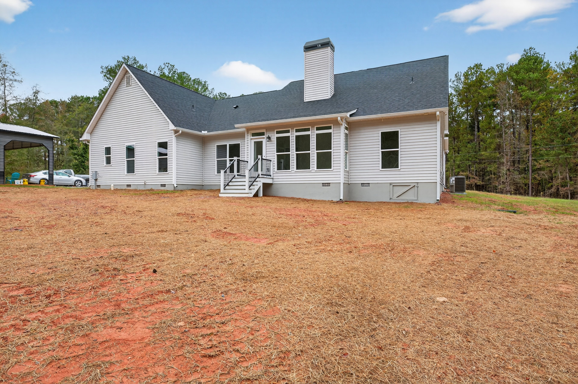 Two-story house with white staircase and black railings, brick chimney, white-framed windows, grassy yard, and several cars parked in driveway