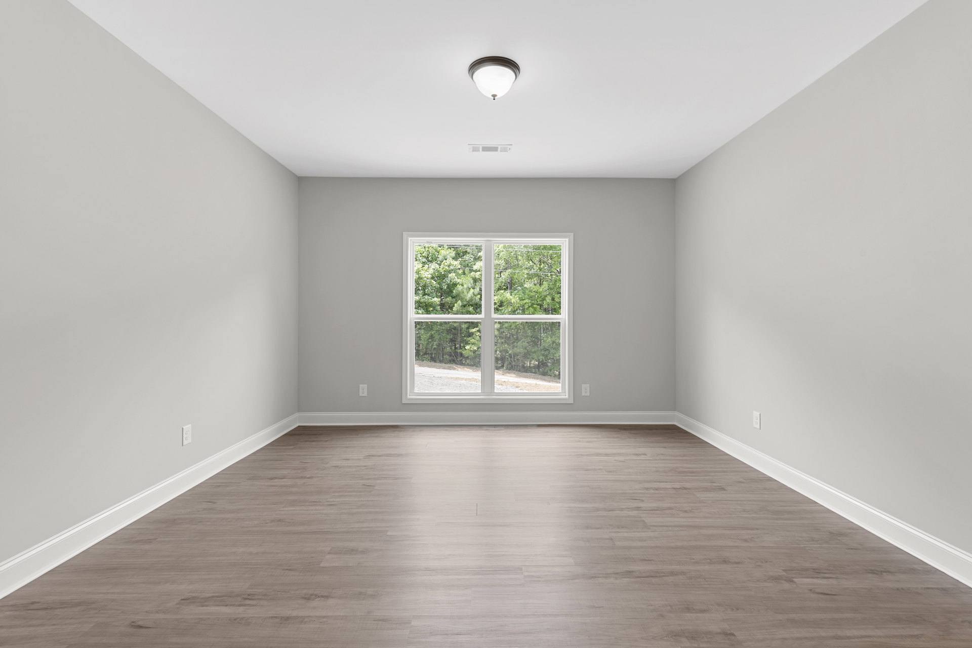 Hardwood flooring with white plaster walls, large window overlooking trees, modern ceiling light fixture