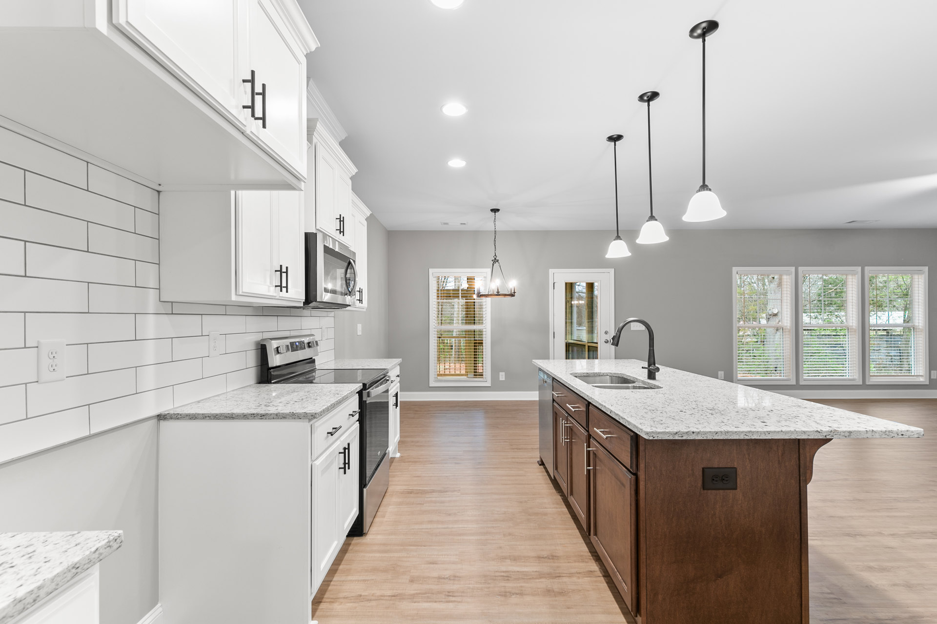 Kitchen with white cabinets, granite countertops, central island featuring sink and faucet, tile flooring, multiple windows with blinds, stainless steel appliances, and recessed