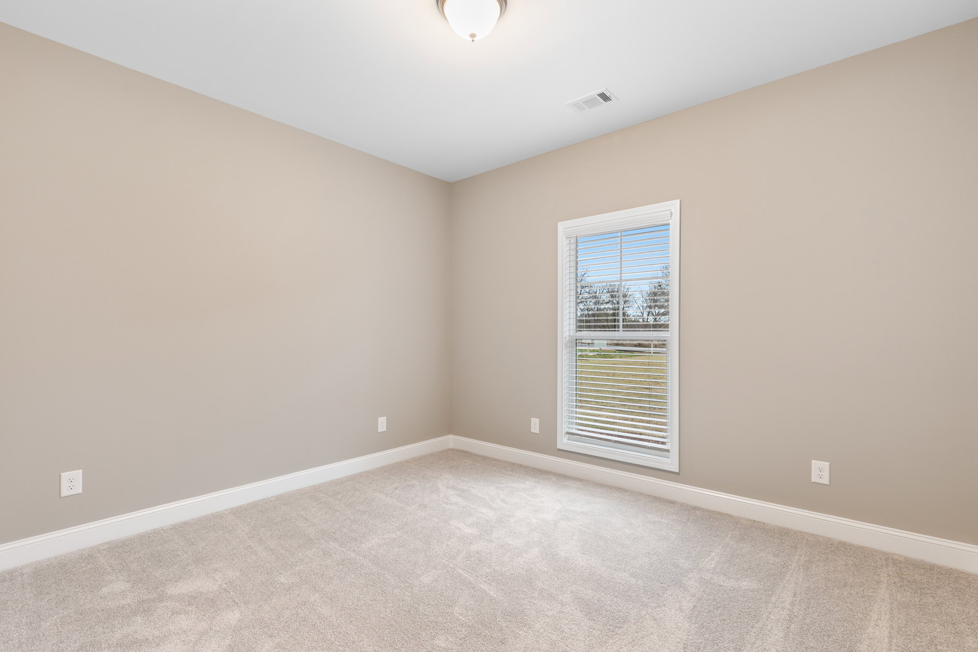Carpeted room with white walls, large window with blinds, white ceiling vent, and recessed light fixture