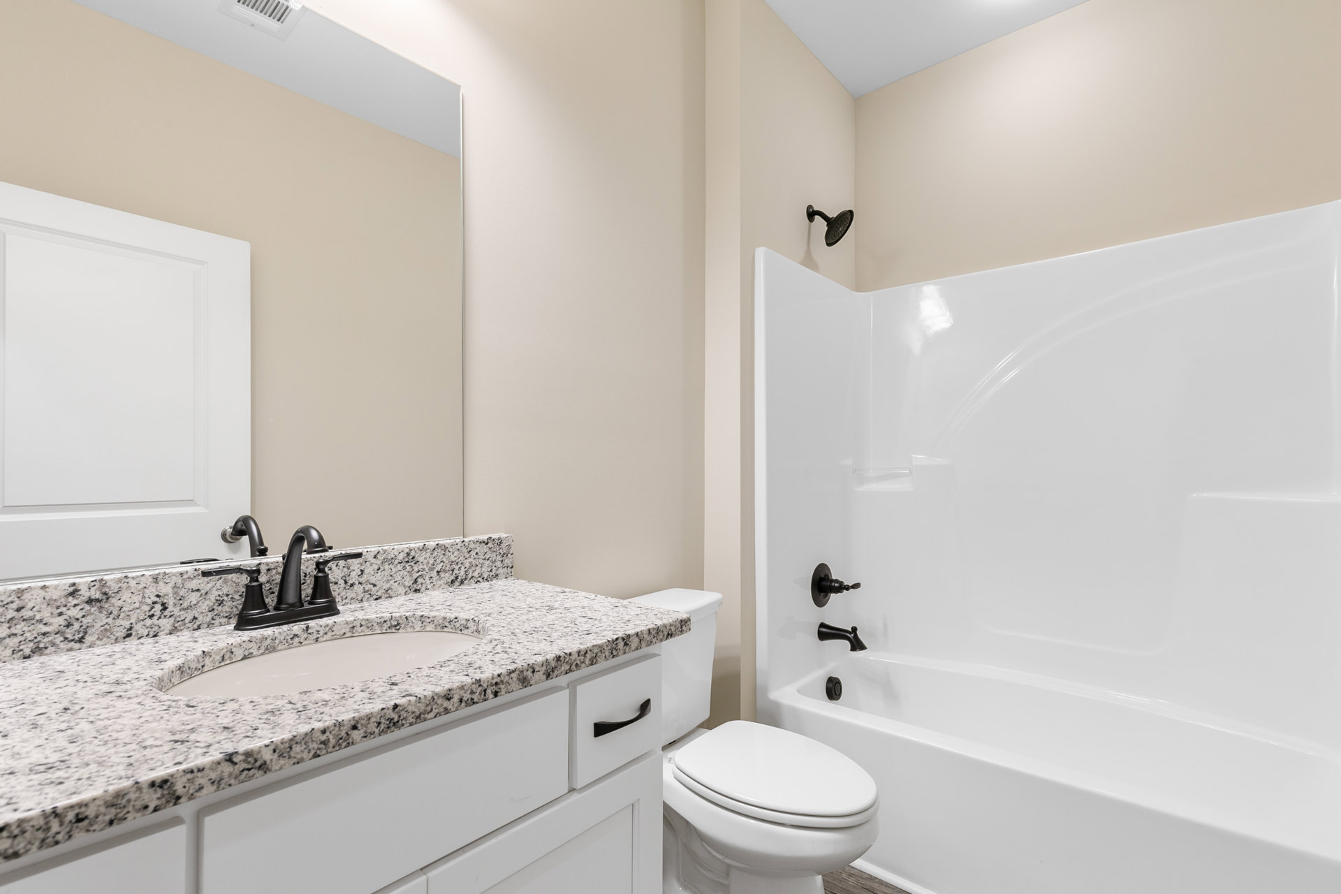 Modern bathroom with white ceramic sink, chrome faucet, white toilet, tiled walls, and a built-in bathtub with a round shower head