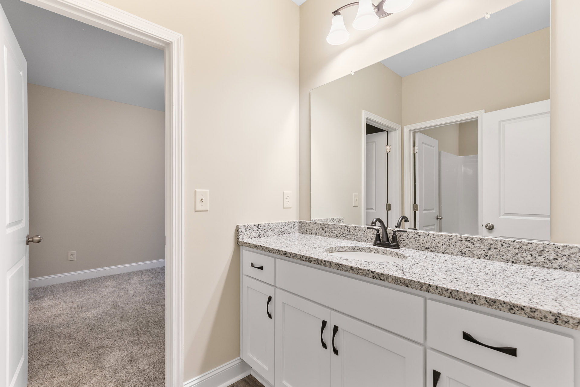 Bathroom with marble countertop, rectangular mirror above sink, white cabinetry, chrome faucet, and light-colored tile flooring