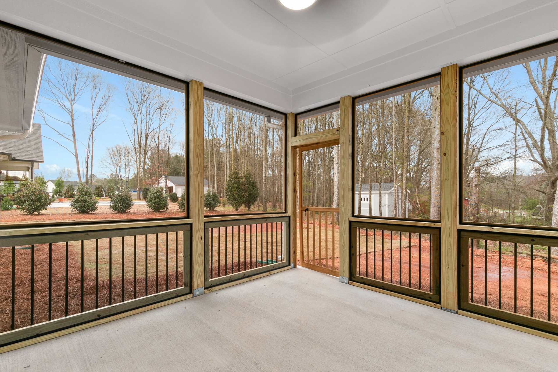 Porch with screened door, wood floor, ceiling light, and view of trees, grass, and neighboring house through large windows