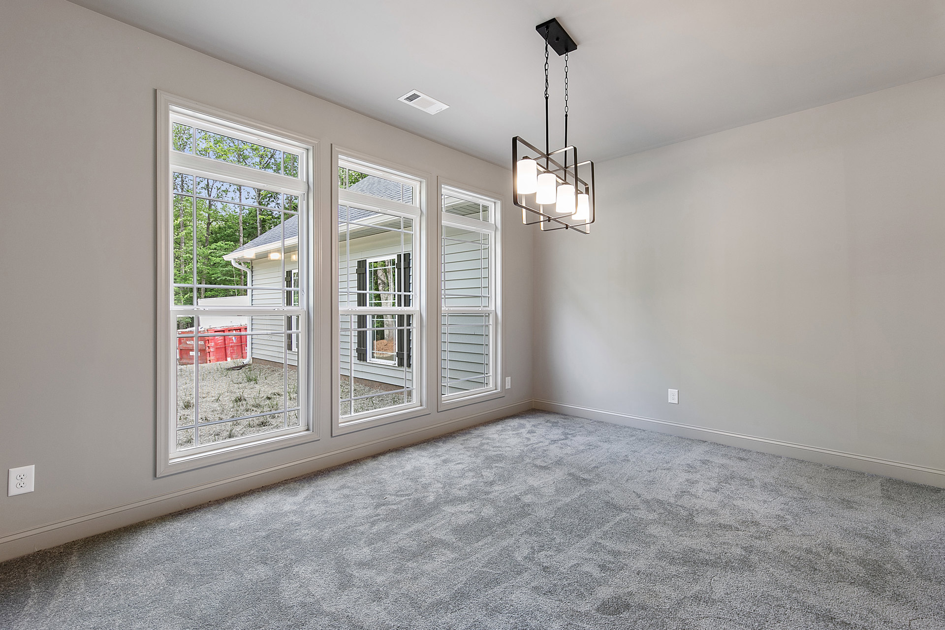 Spacious room featuring large windows, white plaster walls with decorative molding, wood flooring, and an ornate chandelier with white lampshades.