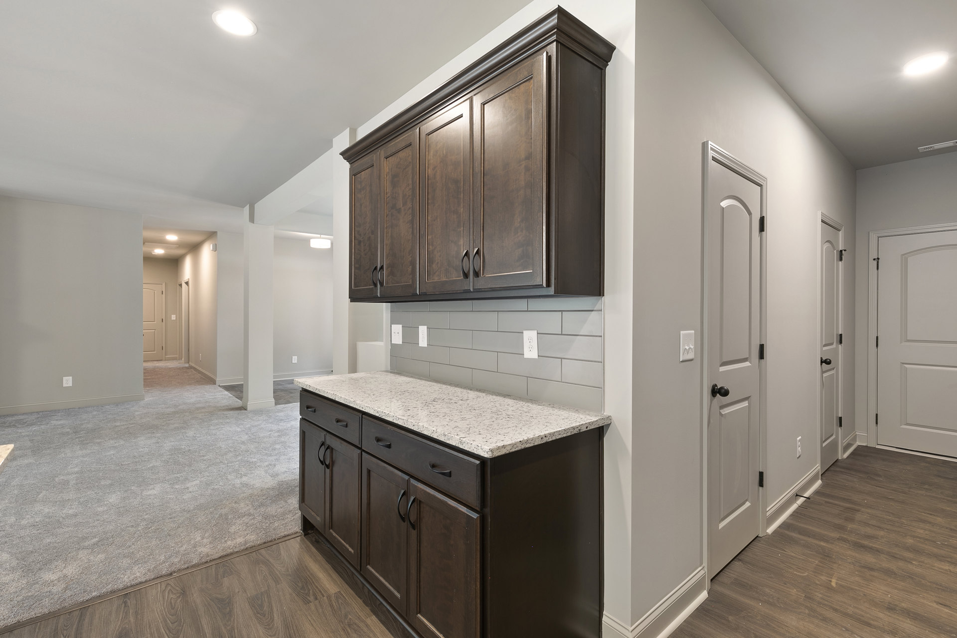 Kitchen with dark wood cabinets, white marble countertop, stainless steel sink, tile backsplash, and hardwood flooring