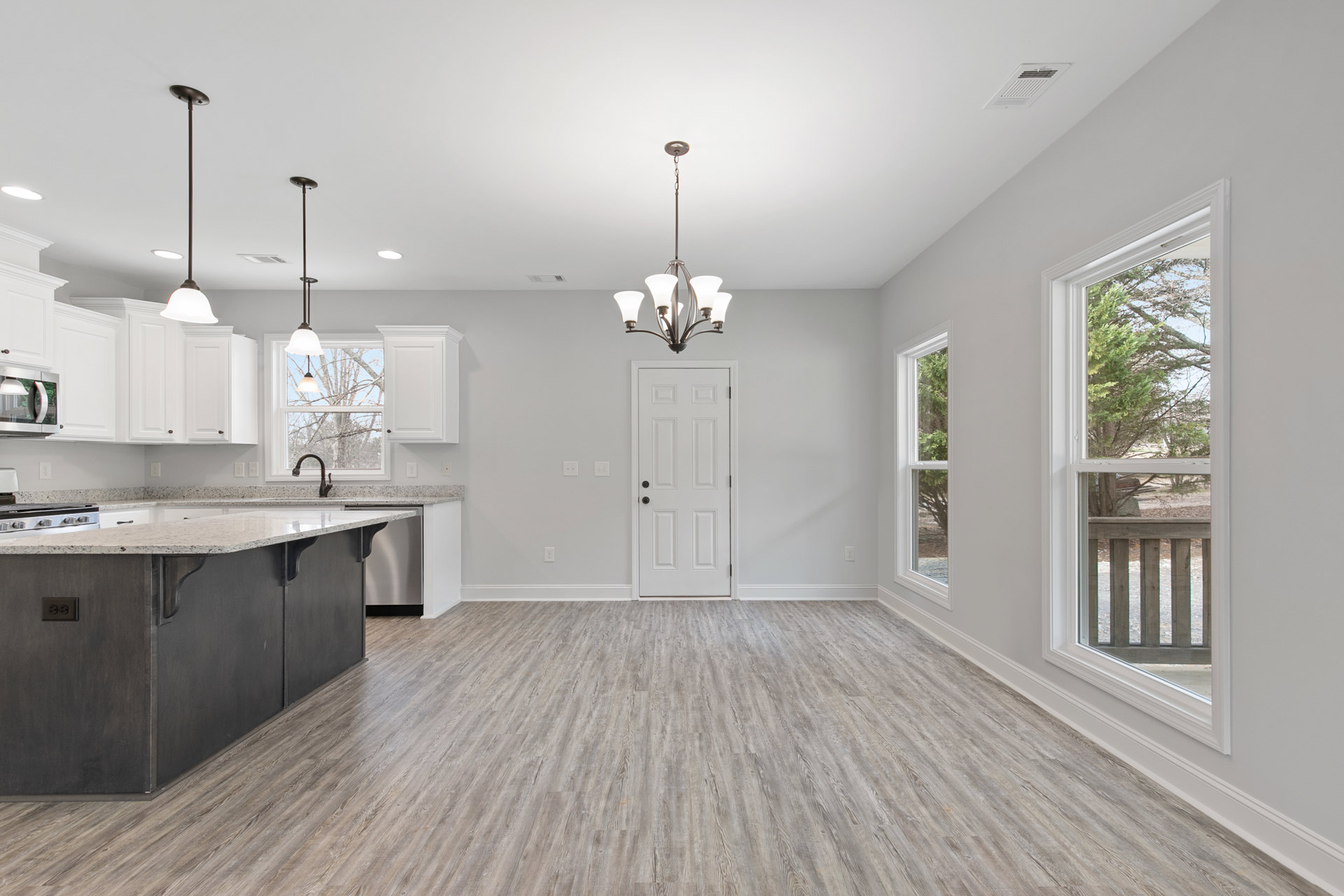 Kitchen with wood flooring, white door with black knobs, marble countertop island, cabinetry, sink, and modern chandelier lighting fixture