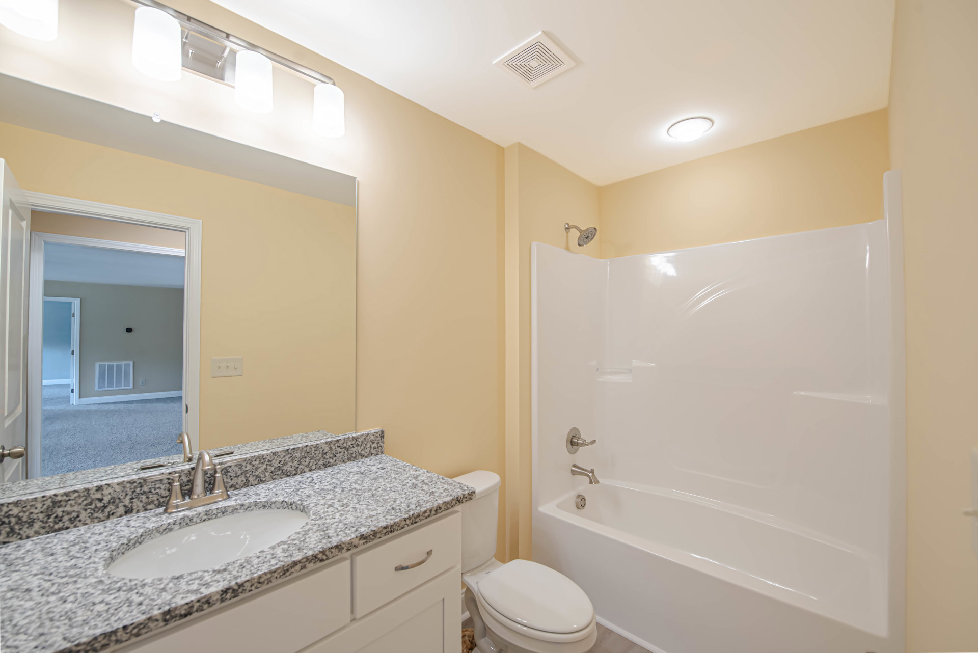 Modern bathroom with white tile walls, built-in shower, rectangular sink with chrome faucet, wall-mounted mirror, and closed white toilet
